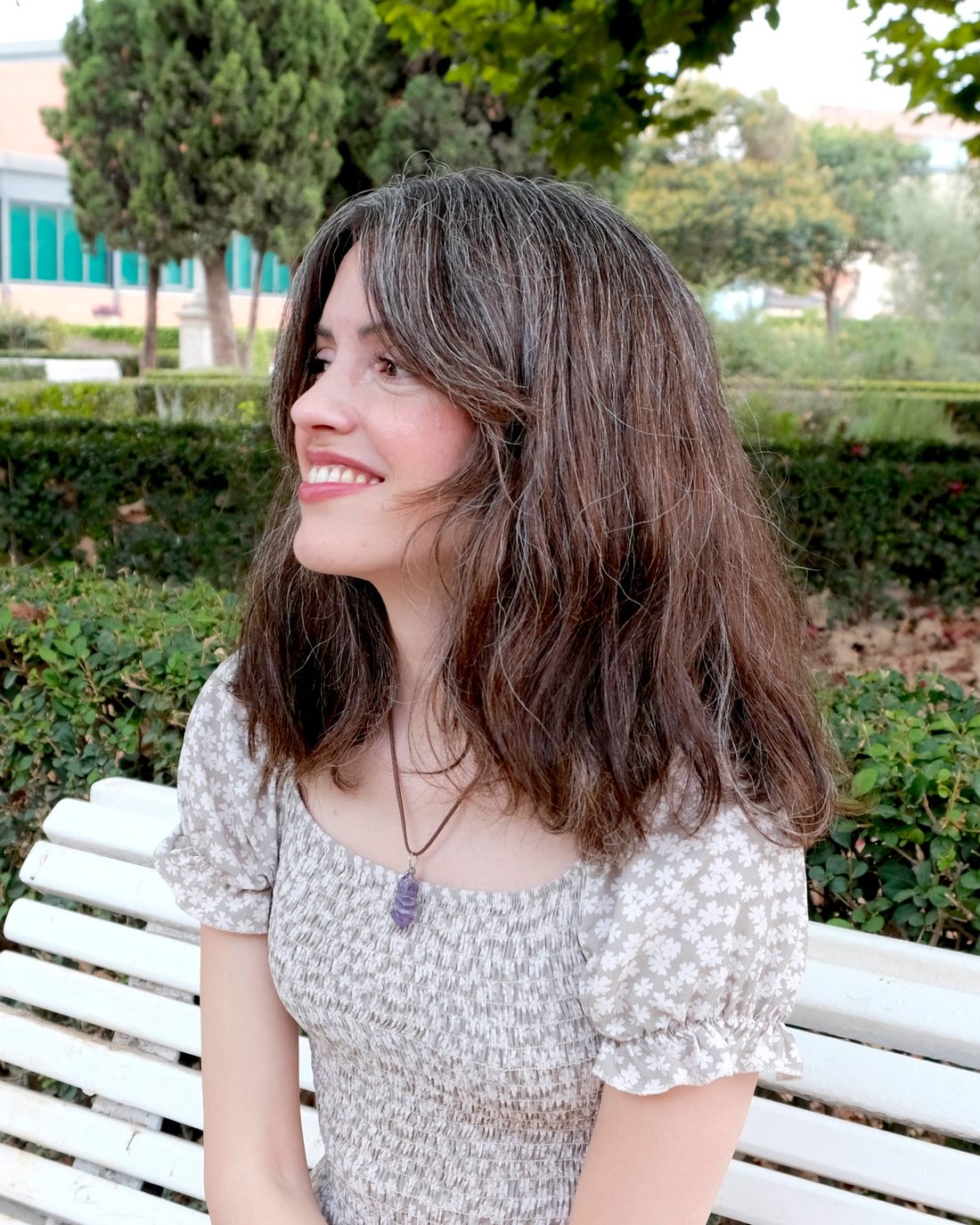 Andrea Picó sonriendo, sentada en un banco de un parque